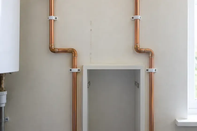Copper water pipes neatly rerouted around a utility-room recess.